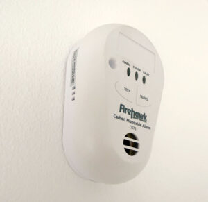 A Carbon monoxide alarm installed vertically on a white painted wall