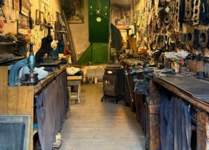 A workshop full of tools and workbenches with a gas heater next to the workbench on the right of the image