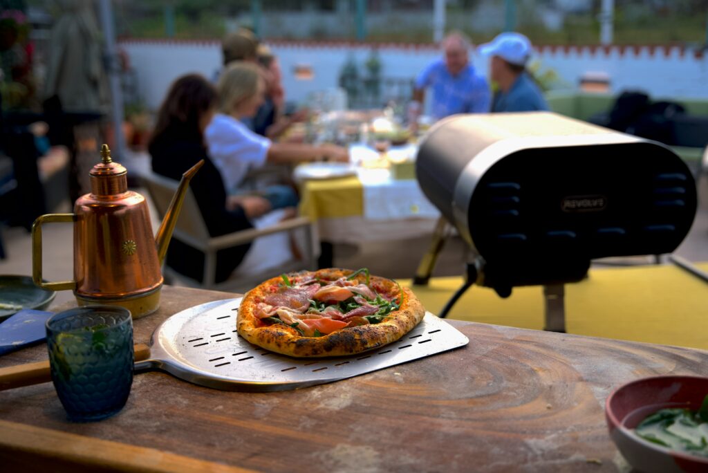 Friends enjoying an autumn evening outdoors with a gas pizza oven